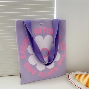 Detail of purple knitted tote bag with white flower pattern and pink lettering texture