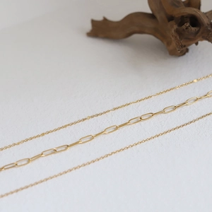 Detailed view of layered 18K gold-plated paperclip and delicate cable chains
