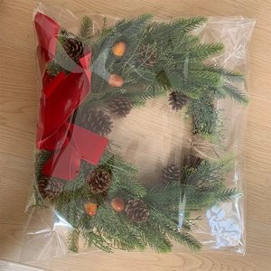Detail view of a Christmas wreath with red bow and pine cones in protective packaging