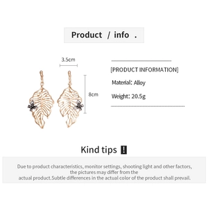 Detailed view of golden leaf earrings with butterfly accent and 3.5cm by 8cm dimensions