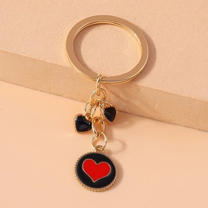 Detail of gold metal keychain featuring black enamel heart charms and red heart pendant