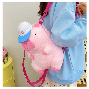 Detail of pink plush pig backpack featuring a stylish blue and white lettered baseball cap