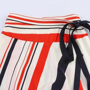 Detail of high waist striped skirt with orange and black lines and side black ribbon bow