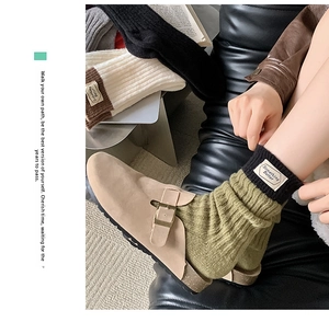 Detail of wool-blend ribbed socks with 'Something Better' label and olive-black contrast