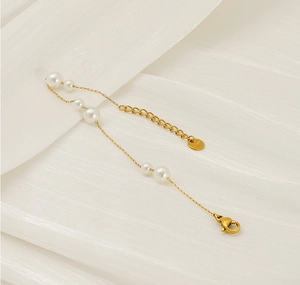 Detail of stainless steel pearl bracelet featuring elegant gold chain and lobster clasp