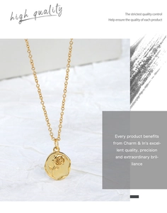 Detail of a gold rose relief pendant on a fine chain over a textured white fabric background