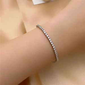 Close-up of a silver-tone tennis bracelet with clear round-cut zircons on a silk background