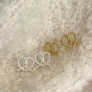 Detail of twisted rope pretzel stud earrings in gold and silver on soft fleece background