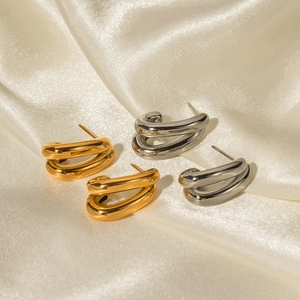 Detailed macro view of gold and silver double-layered C-shaped earrings on satin fabric