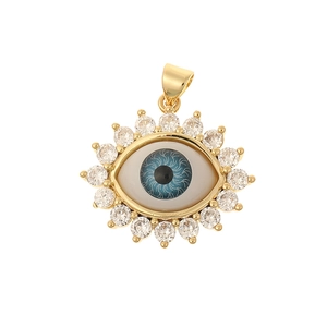 Macro shot of gold devil eye pendant with blue zircon stones on a white background