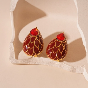 Détail macro de boucles d'oreilles vintage en émail rouge avec motif écailles dorées et gemme