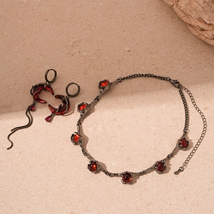 Vintage gothic jewelry set with black alloy thorns and red gemstones on stone background