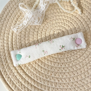 Detail of floral fabric cable organizer on woven mat with heart and round buttons