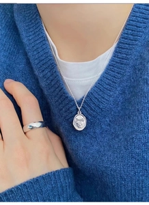 Close-up of a 925 sterling silver smile pendant necklace and simple wide band ring