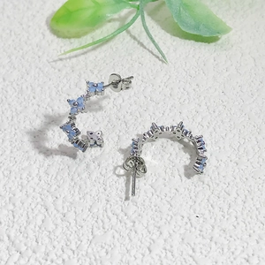 Close-up of silver C-shaped hoop earrings with micro-set light blue zircon flowers