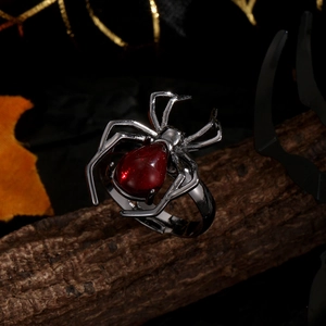 Vue détaillée d'une bague araignée gothique avec gemme rouge sur écorce d'arbre
