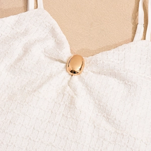Détail d'une robe blanche en tweed 3D avec boucle en métal doré sur l'encolure