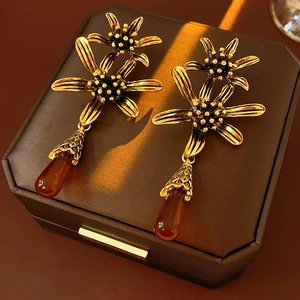 Macro view of vintage gold flower earrings with reddish-brown teardrop pendants