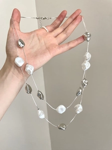 Detail view of double-layered necklace featuring baroque pearls and silver metal beads