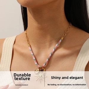 Detail of colorful braided cord and gold plated chain necklace with sun pendants