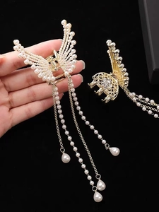 Detailed close-up of golden butterfly hair claw with elegant hanging pearl tassels