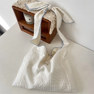 Détail du sac en toile à pois blancs avec bandoulière réglable à nœud et liseré bleu