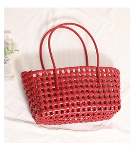 Detail shot of the hollow-out red woven beach bag on white fabric background
