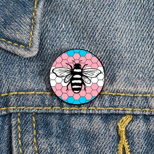 Rainbow bee enamel pin on blue denim jacket featuring transgender pride flag colors