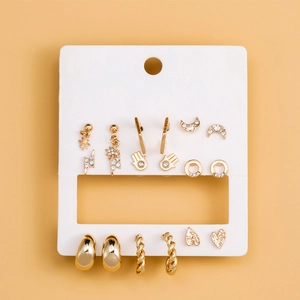 Detailed set of gold earrings with stars, moons, and rhinestones on a white card