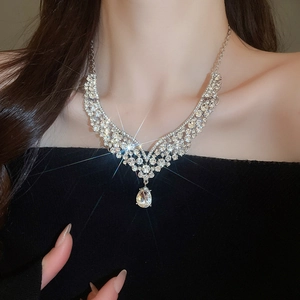 Detailed view of V-shaped rhinestone necklace with pear-cut drop on model at dinner