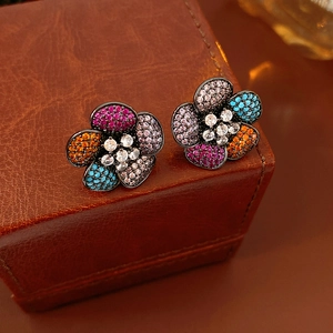 Close-up of vintage flower earrings with colorful zircons on brown leather surface