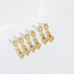 Golden hand-shaped earrings with eye pattern and colorful drip oil accents on white stone