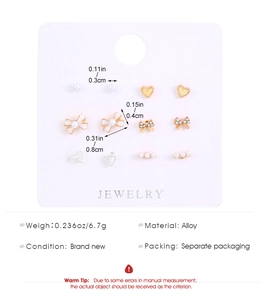 Detalle de set de 6 pares de pendientes dorados con perlas y cristales en tarjeta