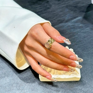 Irregular textured gold open ring with round pink gemstone on a hand with manicure