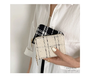 Detailed view of tweed woven texture and metal zipper on compact lady's purses