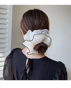 Detail of large white organza scrunchie with black trim on elegant low bun hairstyle