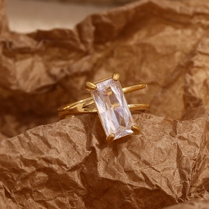 Detail of 18K gold double band ring with rectangular zircon on textured paper background