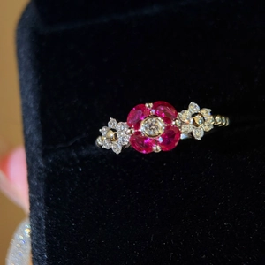 Elegant geometric flower ring with red zircon petals on a luxury black velvet box