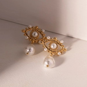 Detailed close-up of vintage gold evil eye earrings with pearls on a soft background