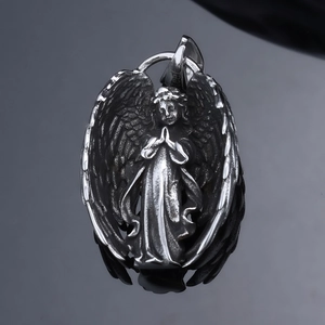 Macro view of silver angel pendant with detailed wings and praying pose on dark surface
