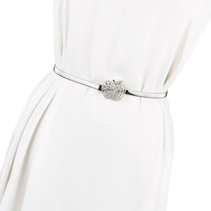 Détail d'une ceinture ressort argentée avec boucle pomme en cristal sur une robe