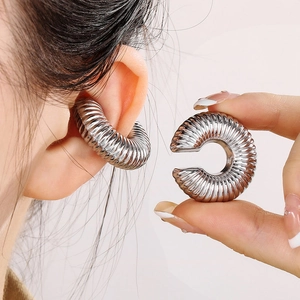 Macro detail of ribbed silver stainless steel ear cuffs showing textured hollow design