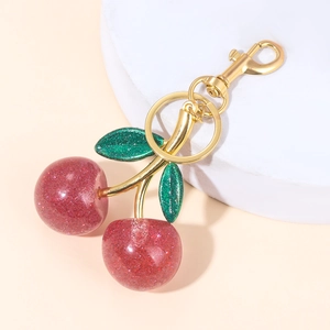Close-up of glittery black cherry keychain with green leaves and gold carabiner clip