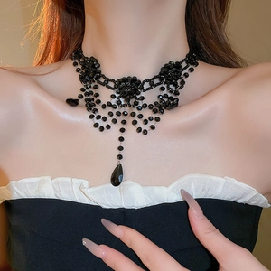 Close-up of black beaded fringe necklace with floral design and teardrop pendant
