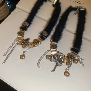 Detail of plush black choker with gold star and cross pendants featuring pearl tassels
