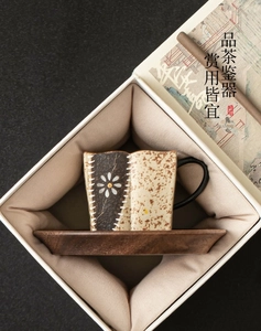 Detail of handmade ceramic tea cup with floral patterns and wooden tray in gift box