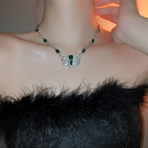 Close-up of silver butterfly necklace featuring green emerald gems and sparkling rhinestones