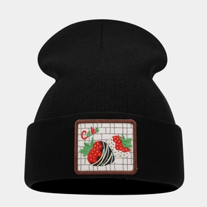 Close-up of black knit beanie featuring a colorful strawberry cake embroidery patch