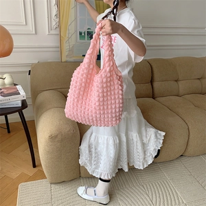Detailed view of pink popcorn textured tote bag showing 3D embossed fabric in a lifestyle setting