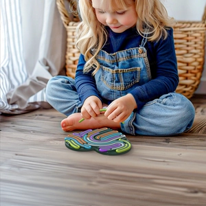 Little girl playing with a colorful silicone sensory maze board on wooden floor